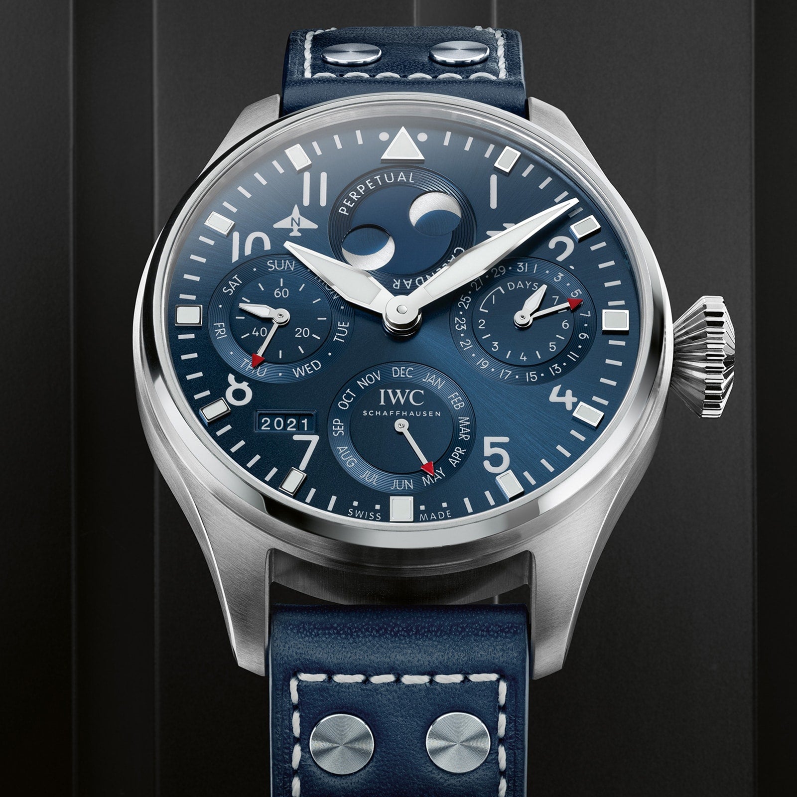 Close-up of the IWC Schaffhausen Big Pilot’s Watch Perpetual Calendar with blue dial, multiple subdials for date, day, month, year, moon phase, a blue leather strap with white stitching, and an IWC-manufactured 52615 calibre.
