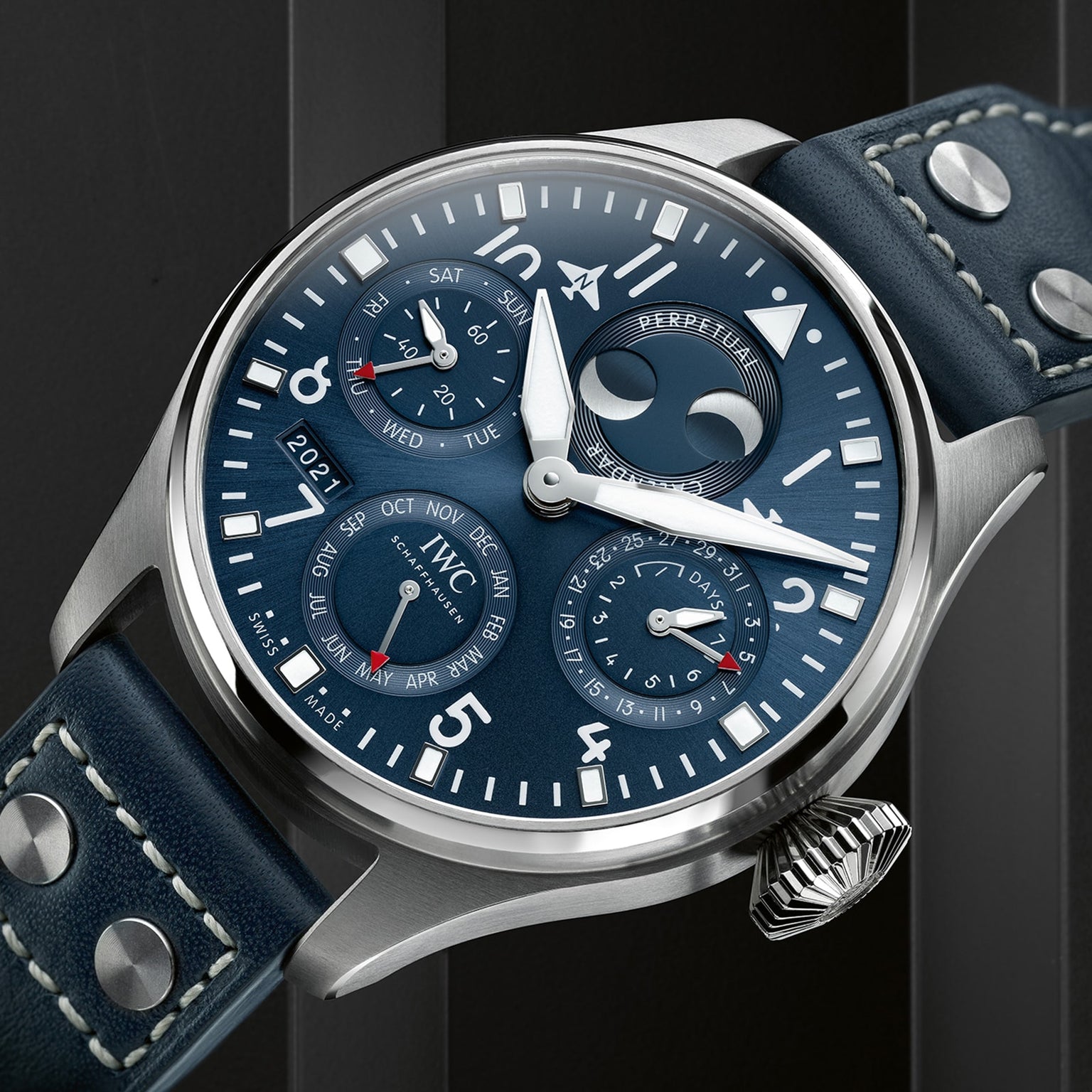 A close-up of the IWC Schaffhausen Big Pilots Watch Perpetual Calendar, featuring a blue dial with white numerals, silver case, leather strap, and subdials for date, day, month, year, and moon phase.