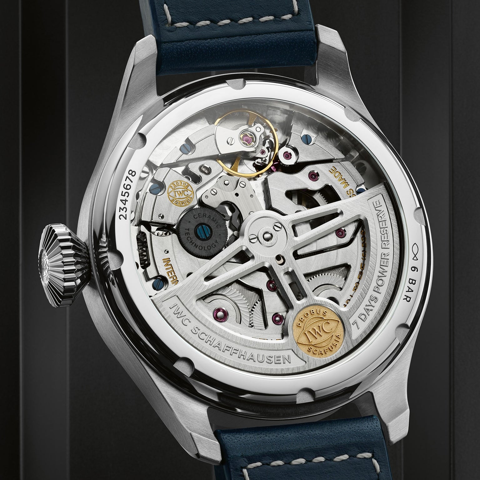 Close-up of the back of IWC Schaffhausen’s Big Pilots Watch Perpetual Calendar, revealing its exposed mechanical movement, labeled components, engraved rotor, IWC-manufactured 52615 calibre, and a blue leather strap.