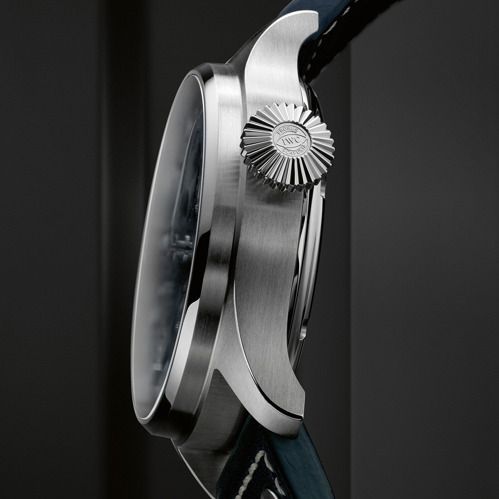 A close-up side view of the IWC Schaffhausen Big Pilots Watch Perpetual Calendar showcases its textured crown with logo, in-house 52615 calibre movement, and black leather strap.