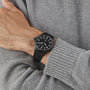 Someone wears an IWC Schaffhausen Big Pilots Watch 43 Top Gun with a black ceramic case and black strap, paired with a light grey knit sweater.