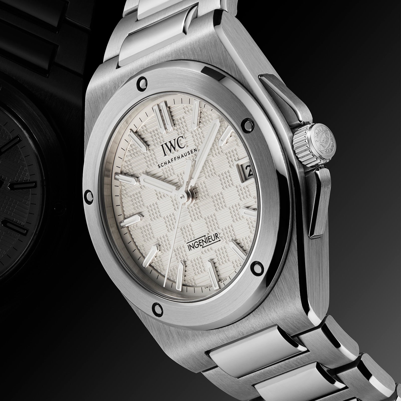 The IWC Schaffhausen Ingenieur Automatic 35 wristwatch features a textured silver dial, date window at 3 o’clock, and metal bracelet, shown angled on a dark background. Inspired by Gérald Genta’s iconic design.