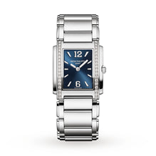 The Patek Philippe Twenty~4 4910/1200A-001 is a silver rectangular wristwatch featuring a blue face and diamond accents on the sides of the case.