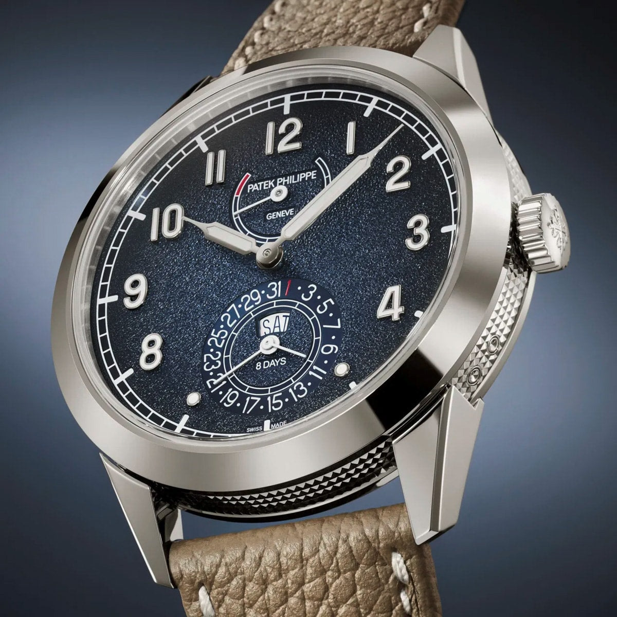 The Patek Philippe Complications 5328G-001 is a luxury wristwatch featuring a textured black dial and a brown leather strap.