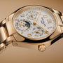 Close-up of a gold Patek Philippe Twenty~4 7340/1R-001 wristwatch featuring a detailed dial displaying day, date, month, and moon phase.