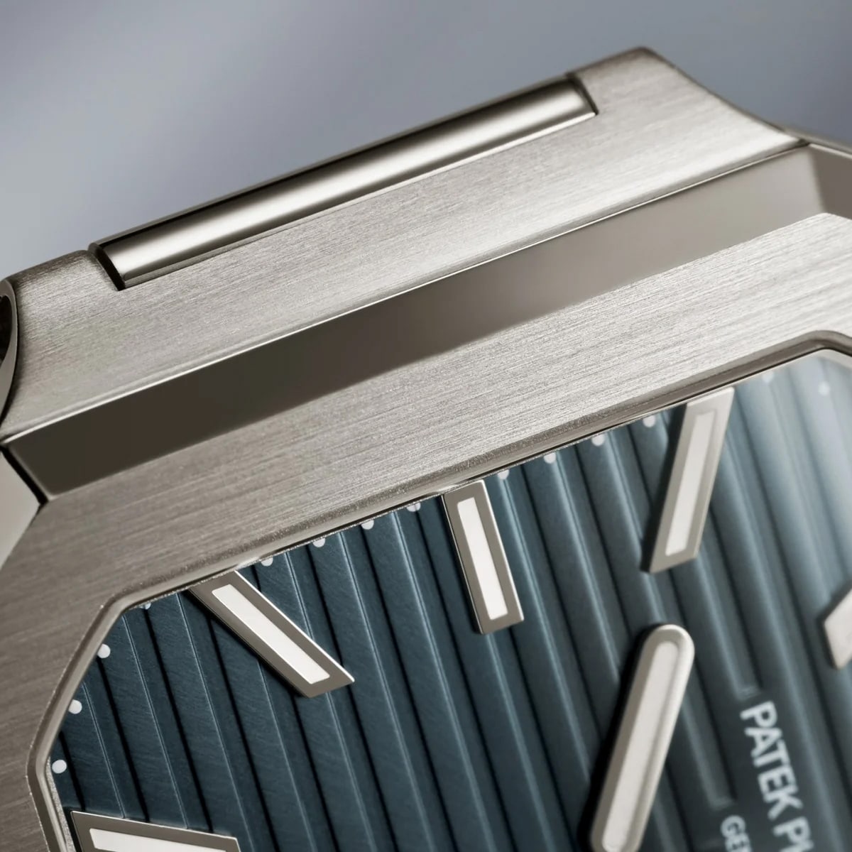 Close-up of the Patek Philippe Cubitus 7128/1G-001 luxury watch face with a brushed metal case and blue textured dial featuring silver hour markers.