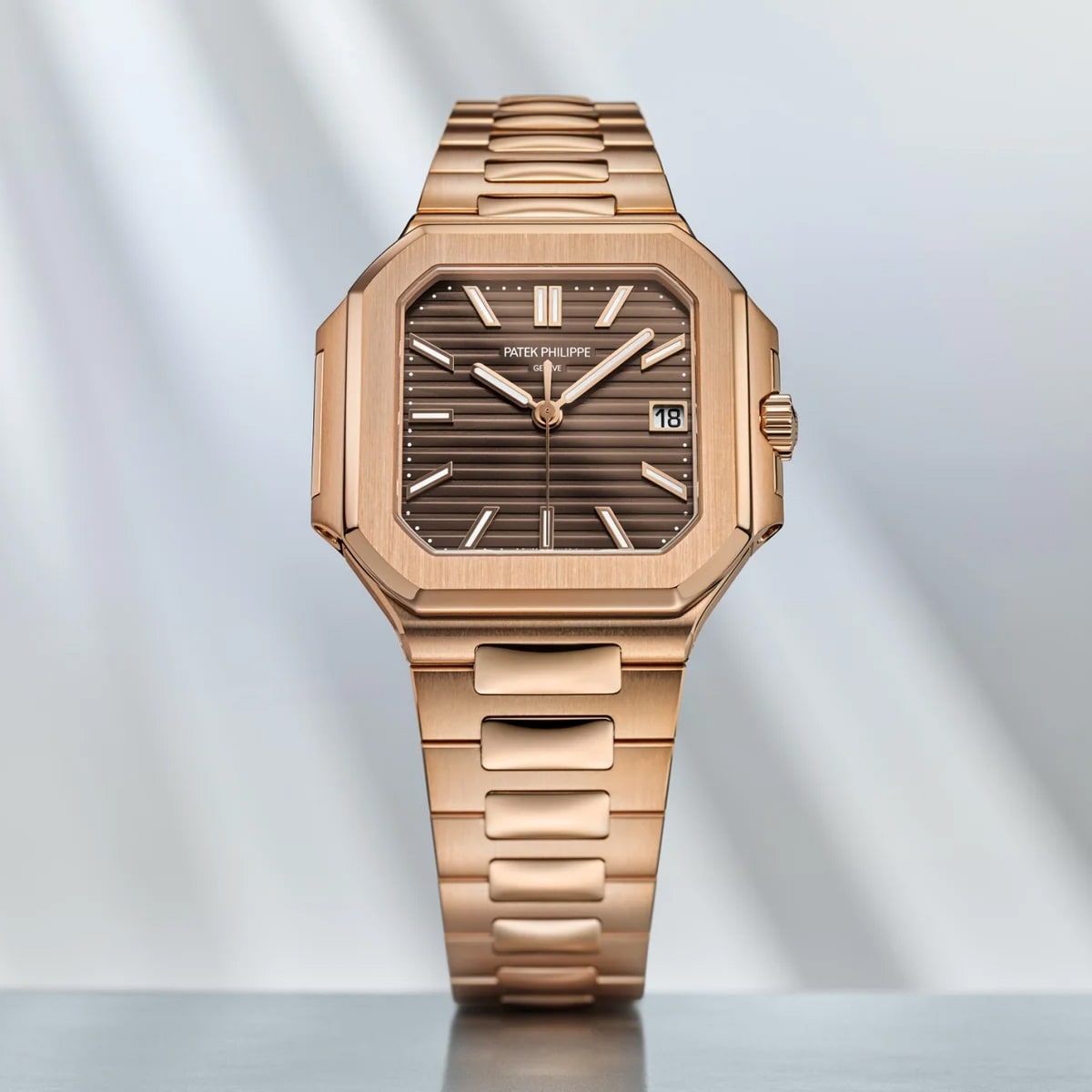 The Patek Philippe Cubitus 7128/1R-001, a rose gold wristwatch with a square dial and brown face, is displayed on a reflective surface.
