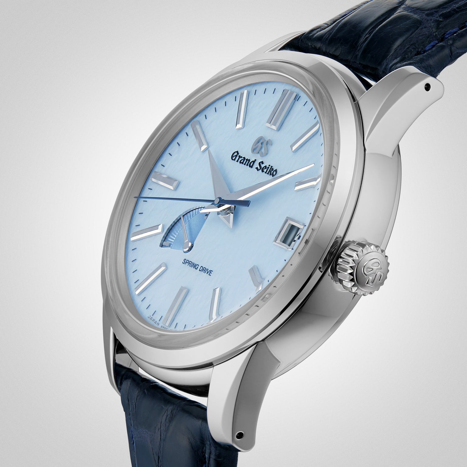 The Grand Seiko Spring Drive Elegance wristwatch features a light blue dial, silver hour markers, a dark blue leather strap, and a stainless steel case, showcasing the brand’s refined craftsmanship.