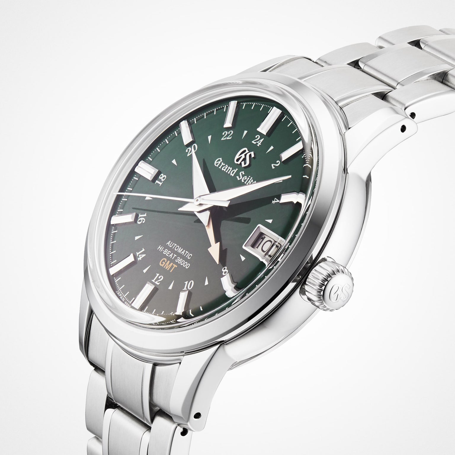 The Grand Seiko Hi-Beat GMT Elegance, a stainless steel wristwatch with a green dial, Calibre 9S86 movement, date window, and silver bracelet, is displayed at an angle on a white background.
