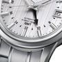 Close-up of the Grand Seiko Hi-Beat GMT Elegance wristwatch, showcasing its textured dial with time, date, and GMT features, plus Automatic Hi-Beat 36000 text and a sleek metal bracelet.