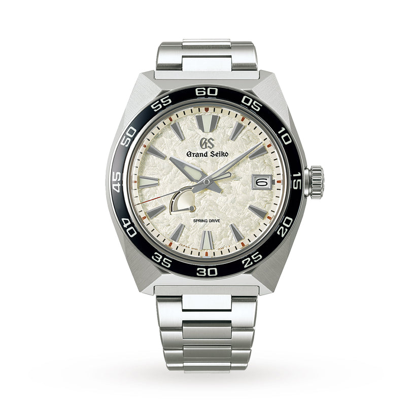 The Grand Seiko Spring Drive Sport wristwatch features a silver lions mane-inspired textured dial, black bezel, date at 3 o’clock, and stainless steel bracelet, displayed against a white background.