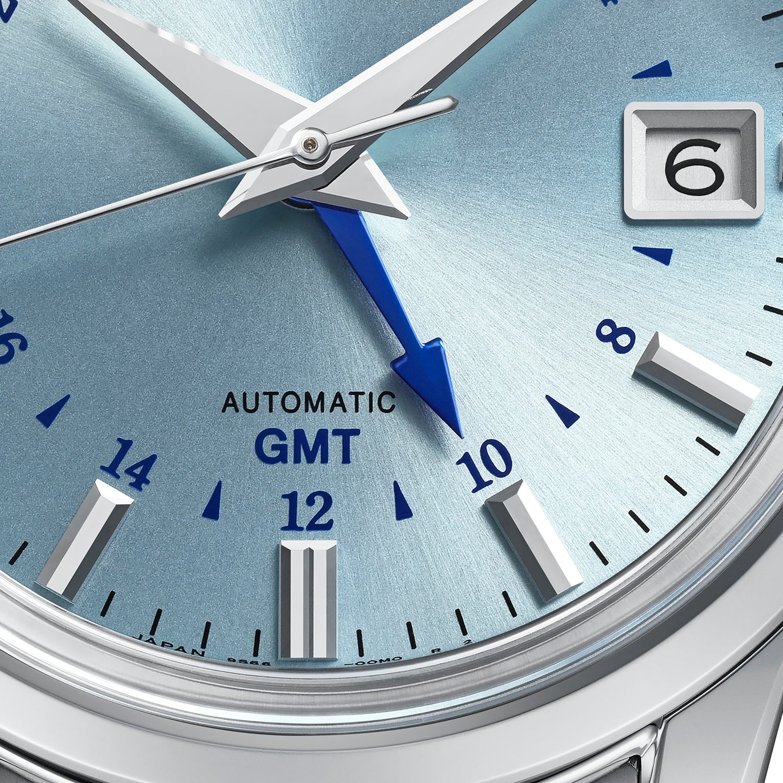 Close-up of the Grand Seiko Automatic GMT Elegance watch face in silver with blue accents, displaying the date window, hands, and Automatic GMT text.