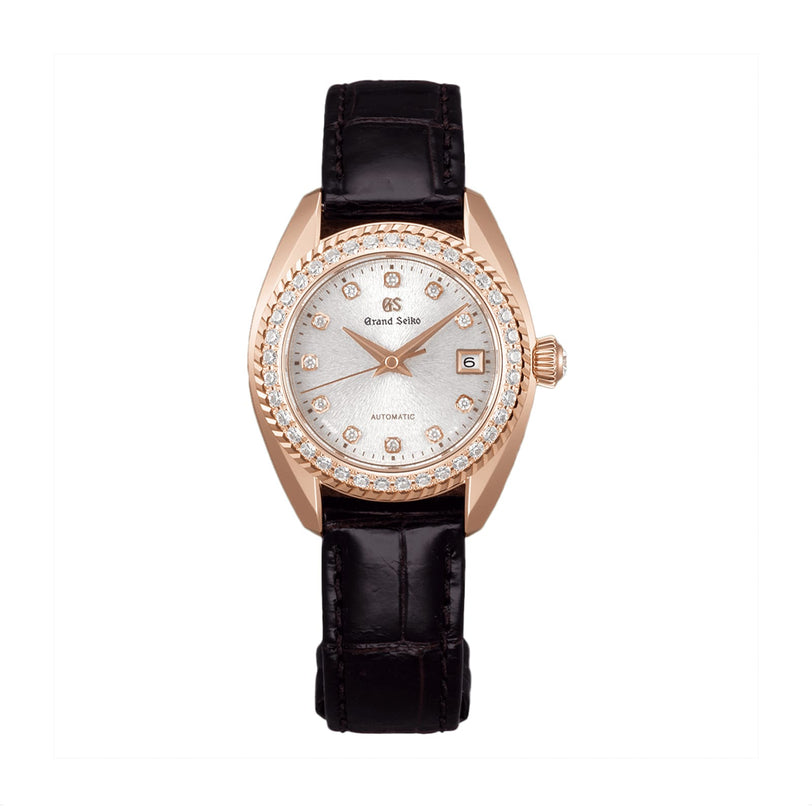 The Grand Seiko Manual Elegance is a ladies’ mechanical watch with a silver dial, diamond hour markers, date display, gold bezel, black leather strap, and the precise Calibre 9S25 movement.