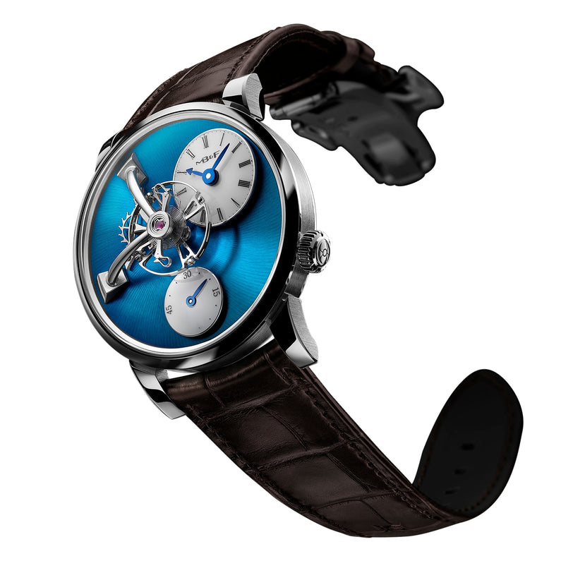 The MB&F Legacy Machine LM101 Steel Blue is a luxury wristwatch featuring a blue dial, brown leather strap, and an exposed mechanical movement.