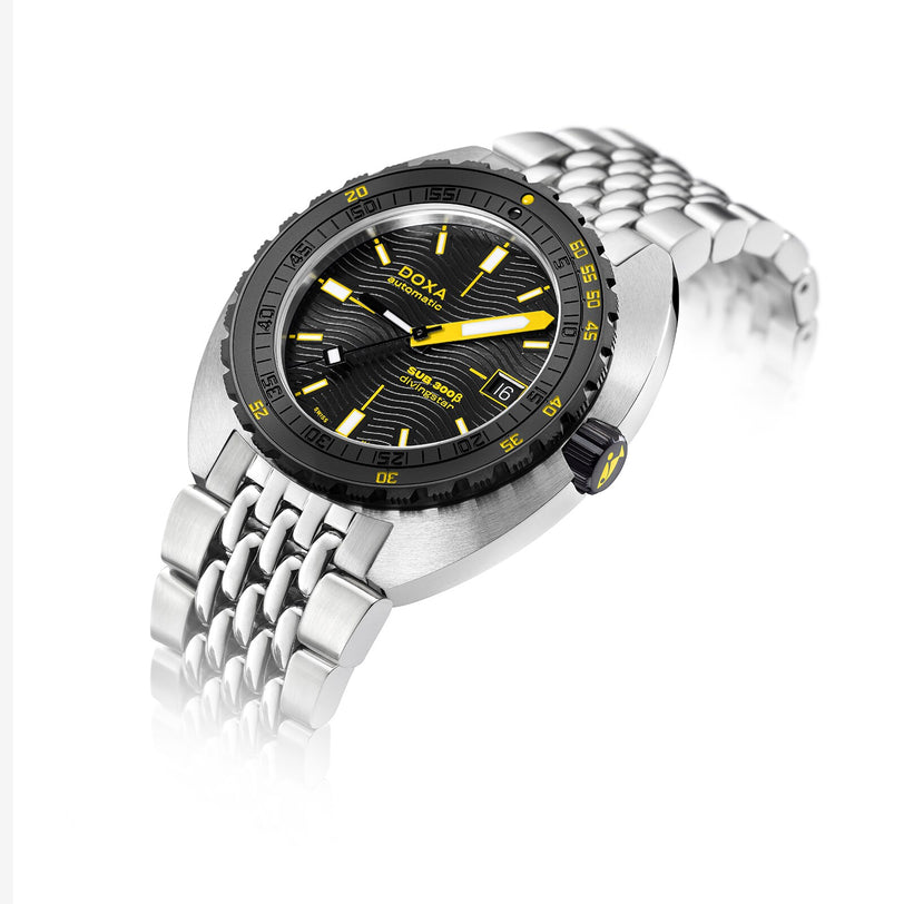 The DOXA Sub 300 Beta Divingstar is a silver sports watch featuring a black and yellow dial, black ceramic bezel, metal bracelet, and Swiss automatic movement, shown on a white background.