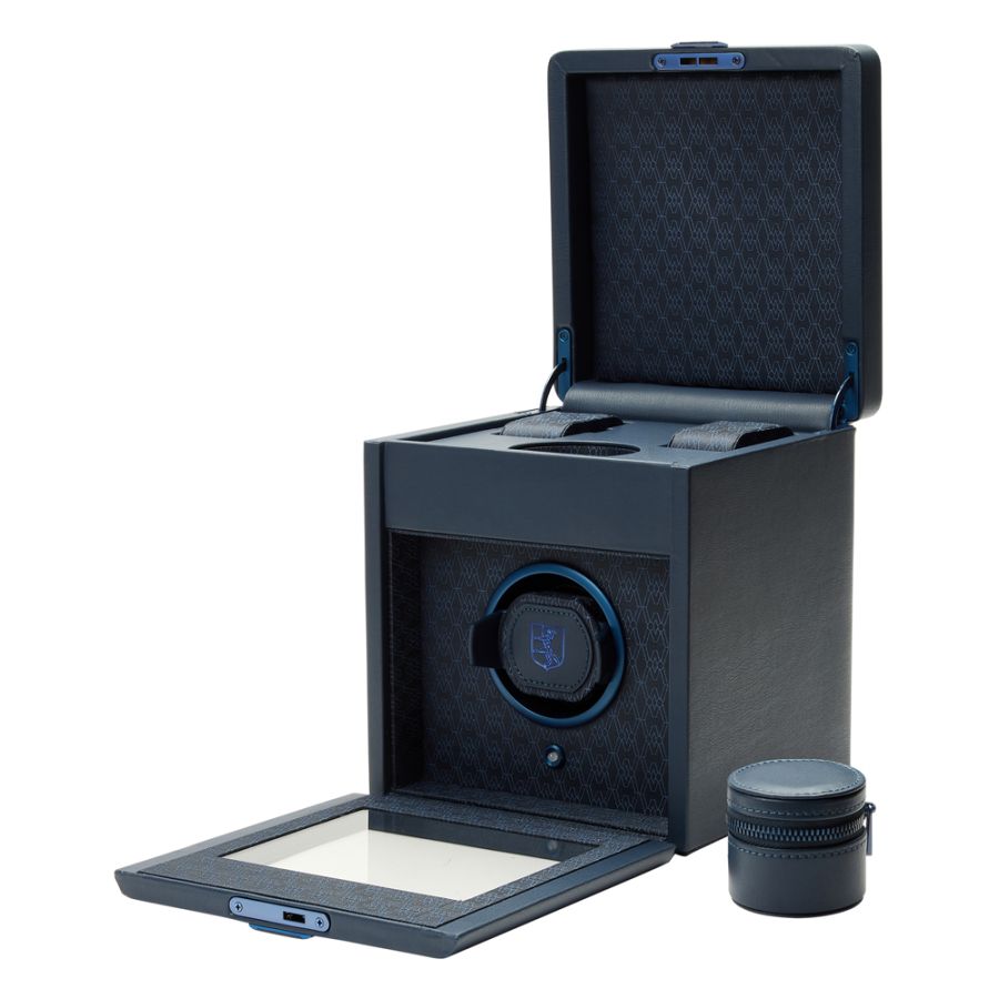 Black watch winder with open lid showing interior cushioned platform, circular winding mechanism on front, and detachable sto