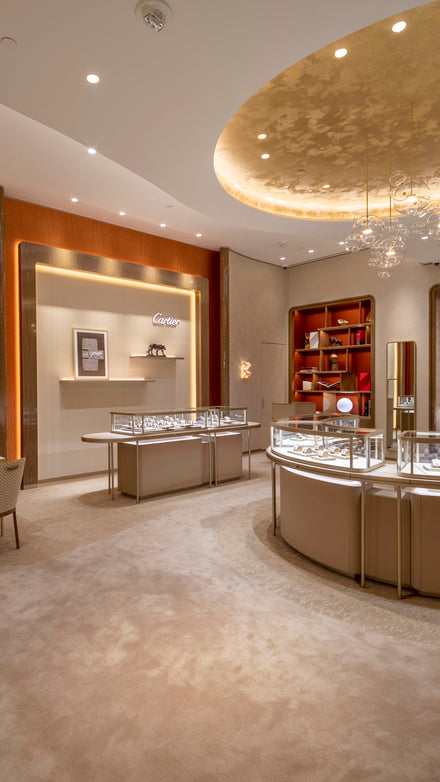 Elegant jewelry store interior with glass display cases, warm lighting, and a gold-accented ceiling.