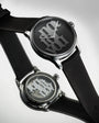 Black watch with a unique face design on a light gray background