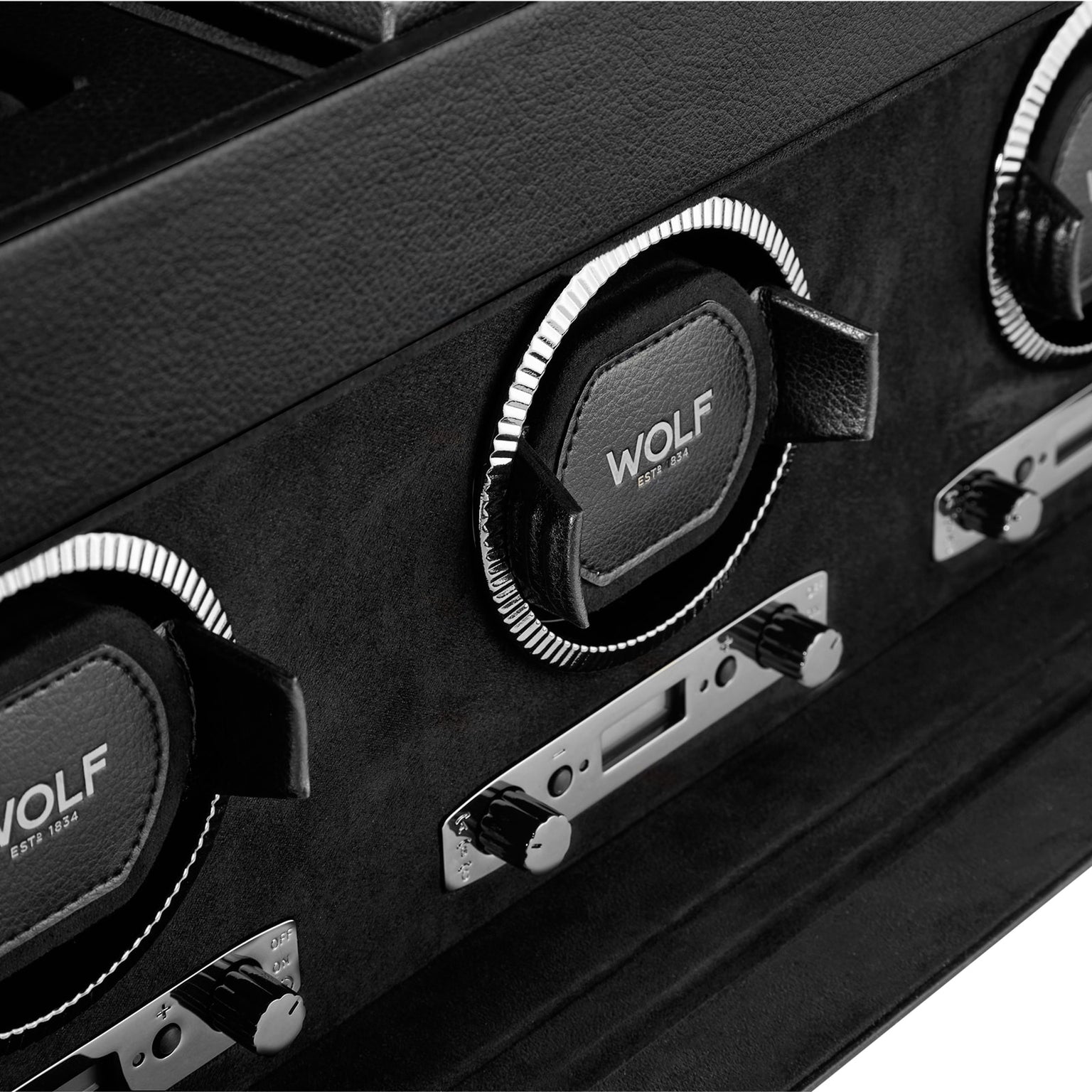 Close-up of a WOLF British Racing Triple Watch Winder with storage, featuring three watch holders and control knobs.