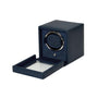 The WOLF Cub Single Watch Winder with Cover is shown in navy blue, featuring a partially open glass lid that reveals the watch holder inside.