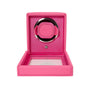 The WOLF Cub Single Watch Winder with Cover is shown open, revealing its circular holder inside. The bright pink finish adds a stylish touch to this elegant watch accessory.