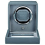 Blue-gray leather watch winder with single rotating cup, chrome accents, and hinged cover.