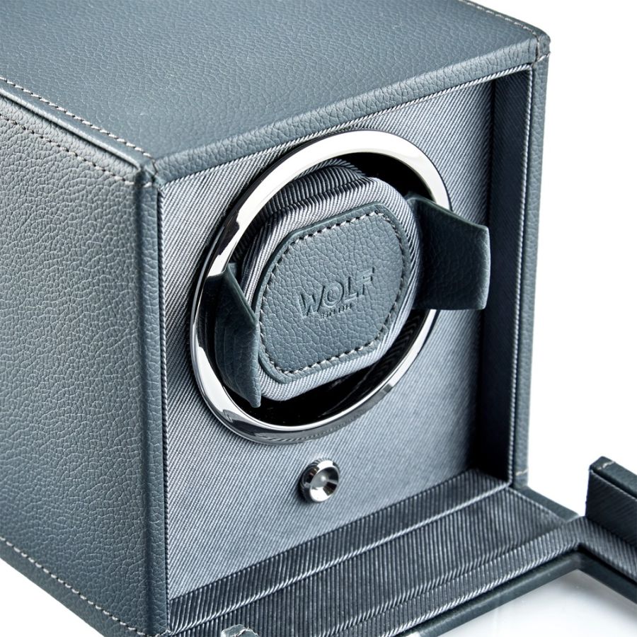 Gray leather watch winder with white and black rotating cup, open cover displaying interior mechanism.