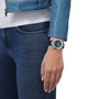 Person wearing a blue jacket and jeans with a watch on a white background