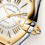 Cartier automatic watch with white dial, gold Roman numerals, date window, and two-tone gold and steel case.