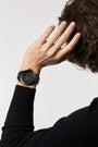 Person wearing a black wristwatch on a plain background