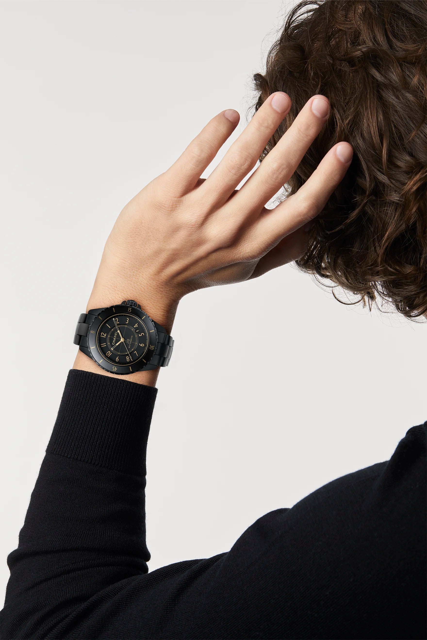 Person wearing a black wristwatch on a plain background
