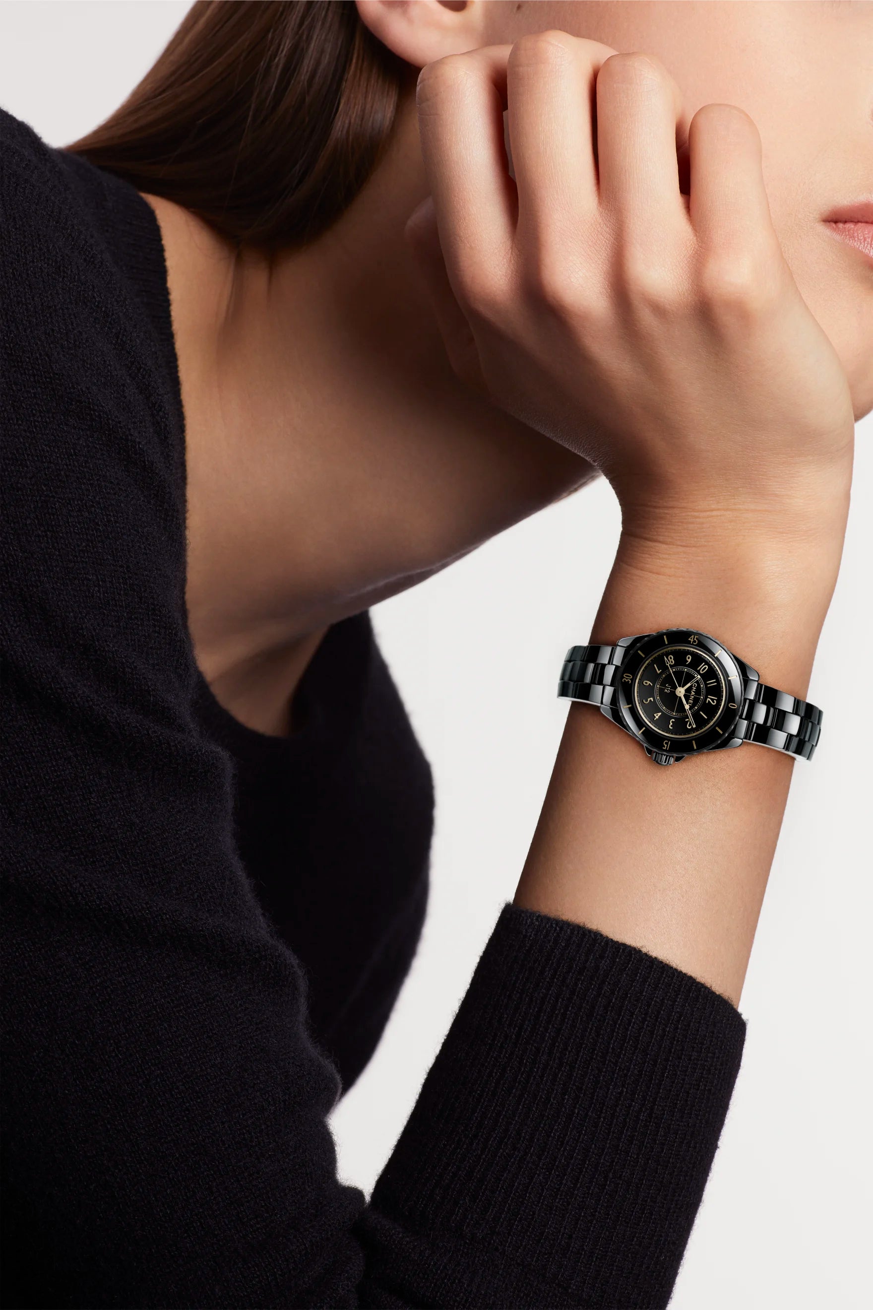 Person wearing a black watch on a plain background