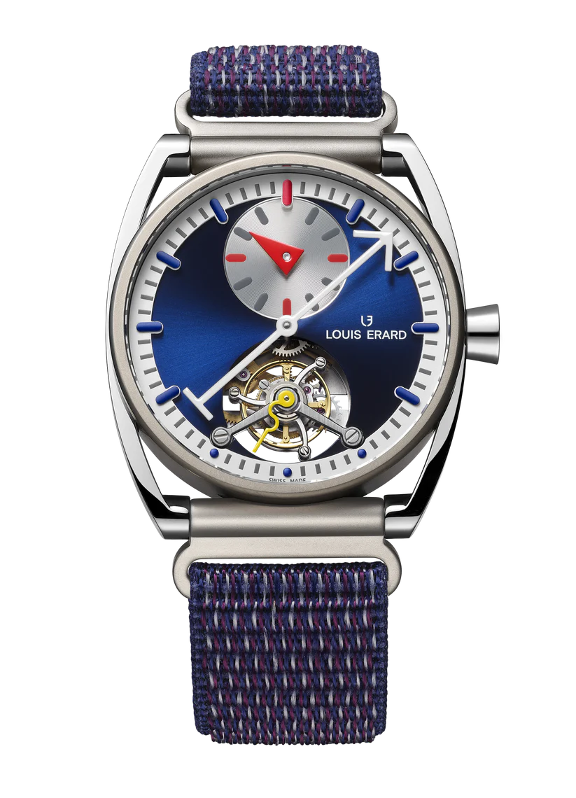 Steel watch with blue dial, visible tourbillon mechanism, small subdial, red triangle hour hand, and blue textile strap.