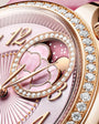 Rose gold watch with pink dial, moon phase complication, crystal diamond bezel, and gold hour markers.
