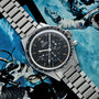 A Watches of Switzerland Speedmaster Ed White watch rests on a magazine page featuring astronauts floating in space.