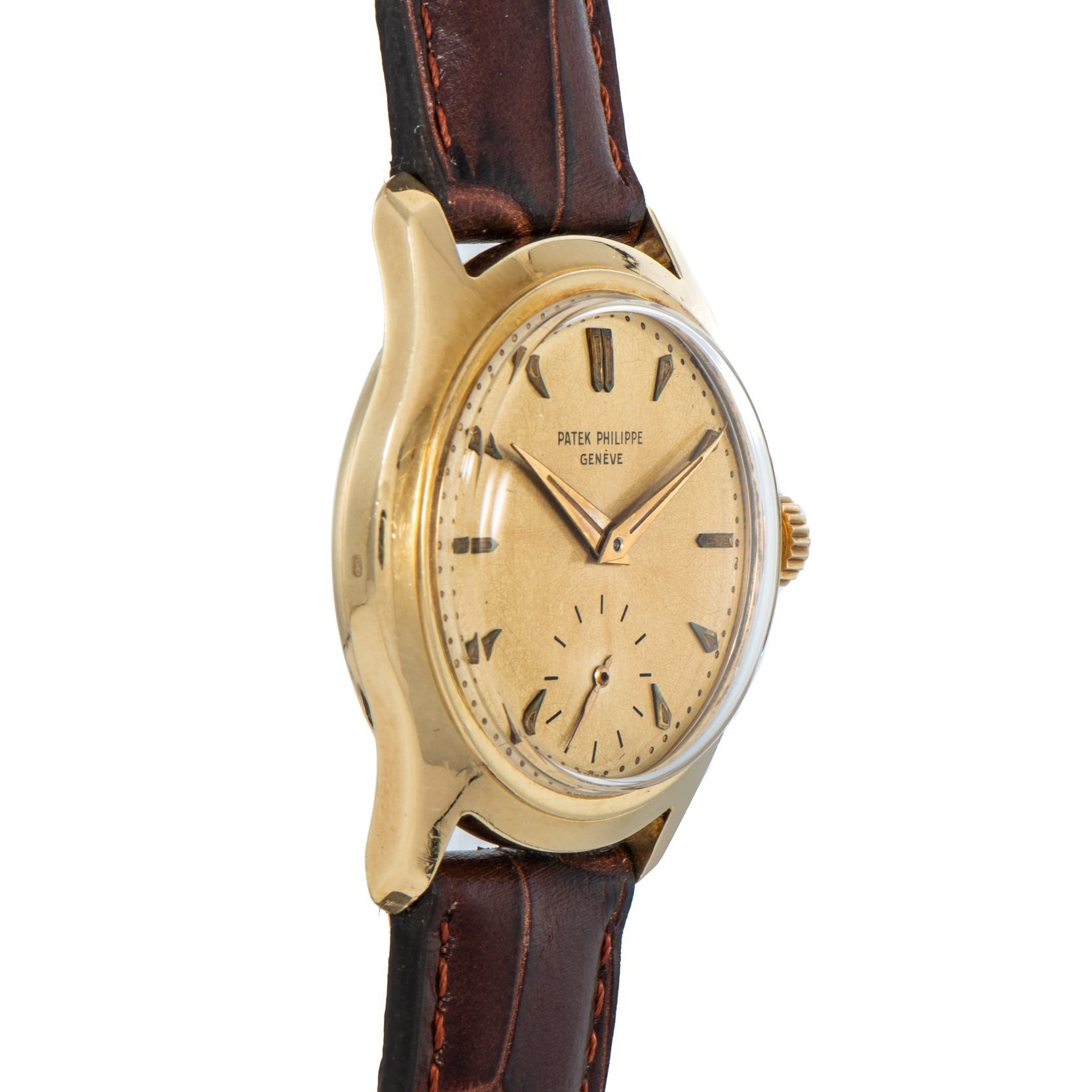 Patek Philippe Calatrava gold vintage wristwatch with a brown leather strap and minimalist dial, shown from an angled perspective.