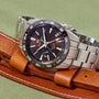 Watch with brown leather strap and silver metal case on green background