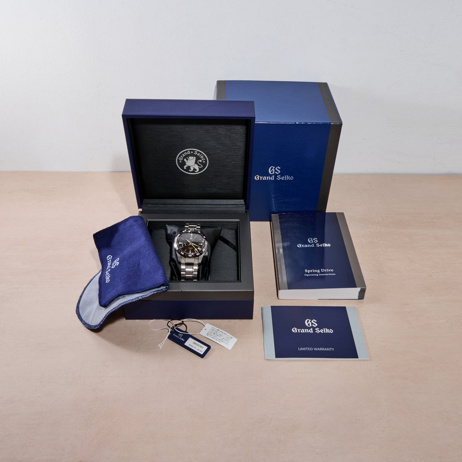 Grand Seiko watch in an open box with accessories on a beige surface