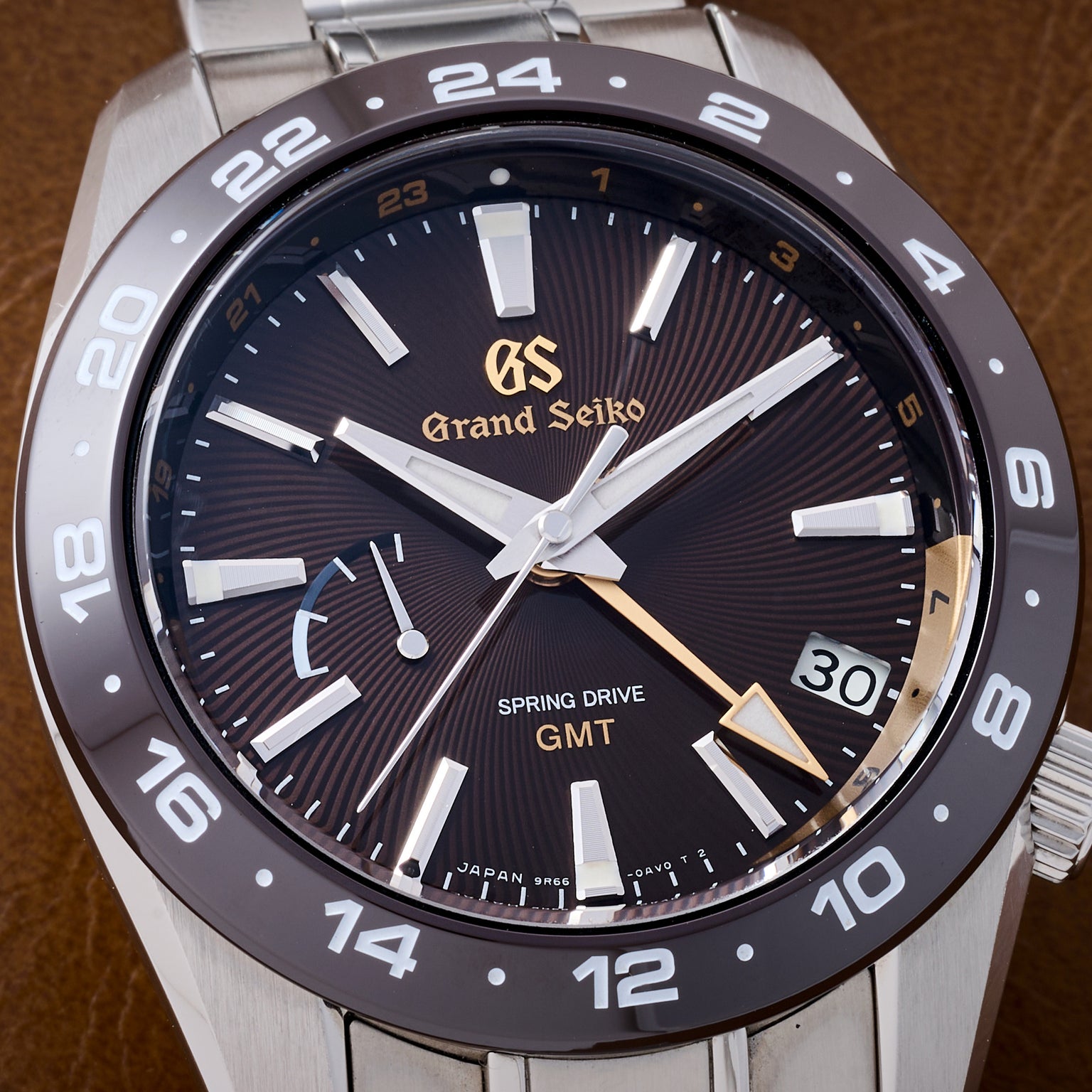 Grand Seiko watch with black dial and silver case on a brown background