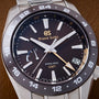 Grand Seiko watch with black dial and silver case on a brown background