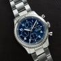 Breitling Navitimer 8 Chronograph watch with a blue dial and metal bracelet, displayed on a dark surface.