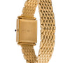 Gold-toned rectangular watch with quilted link bracelet and black crown detail.