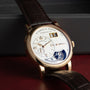The Lange & Sohne Lange 1 Tourbillon is a luxury wristwatch featuring a white dial, gold case, and brown leather strap.