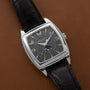 A Patek Philippe Gondolo Annual Calendar wristwatch with a black leather strap on a brown leather surface.
