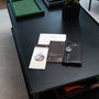A Patek Philippe Calatrava wristwatch and branded booklets are neatly arranged on a black table.