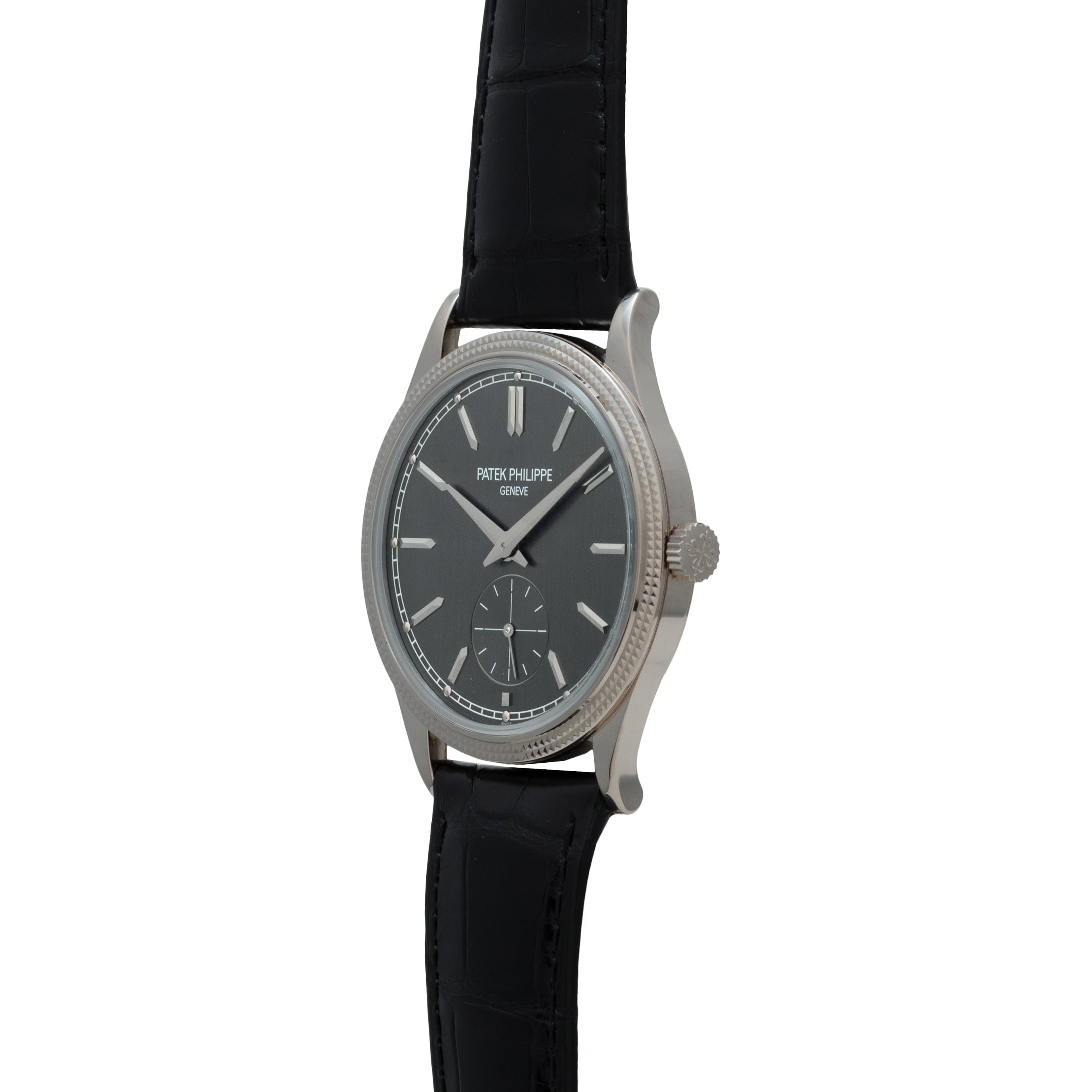 A Patek Philippe Calatrava wristwatch in silver, featuring a black leather strap and dark dial, displayed at an angle.