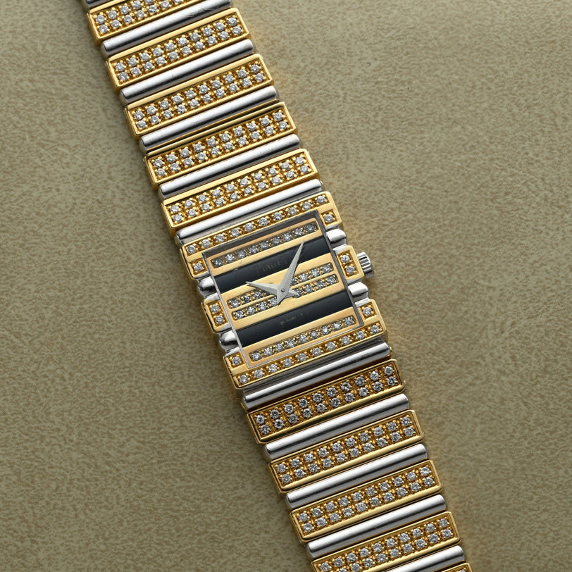 The Piaget Polo Pave is a gold and silver rectangular watch with diamond accents, shown on a textured beige surface.