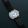 The Cartier Vendome Diamond watch features Roman numerals and a black strap, displayed on a dark textured surface.