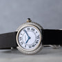 A Cartier Vendome Diamond watch with Roman numerals, a diamond bezel, and a black strap is shown on a gray background.