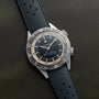 A Jaeger-LeCoultre Deep Sea Alarm U.S. Edition wristwatch with a black strap and black dial displayed on a dark surface.